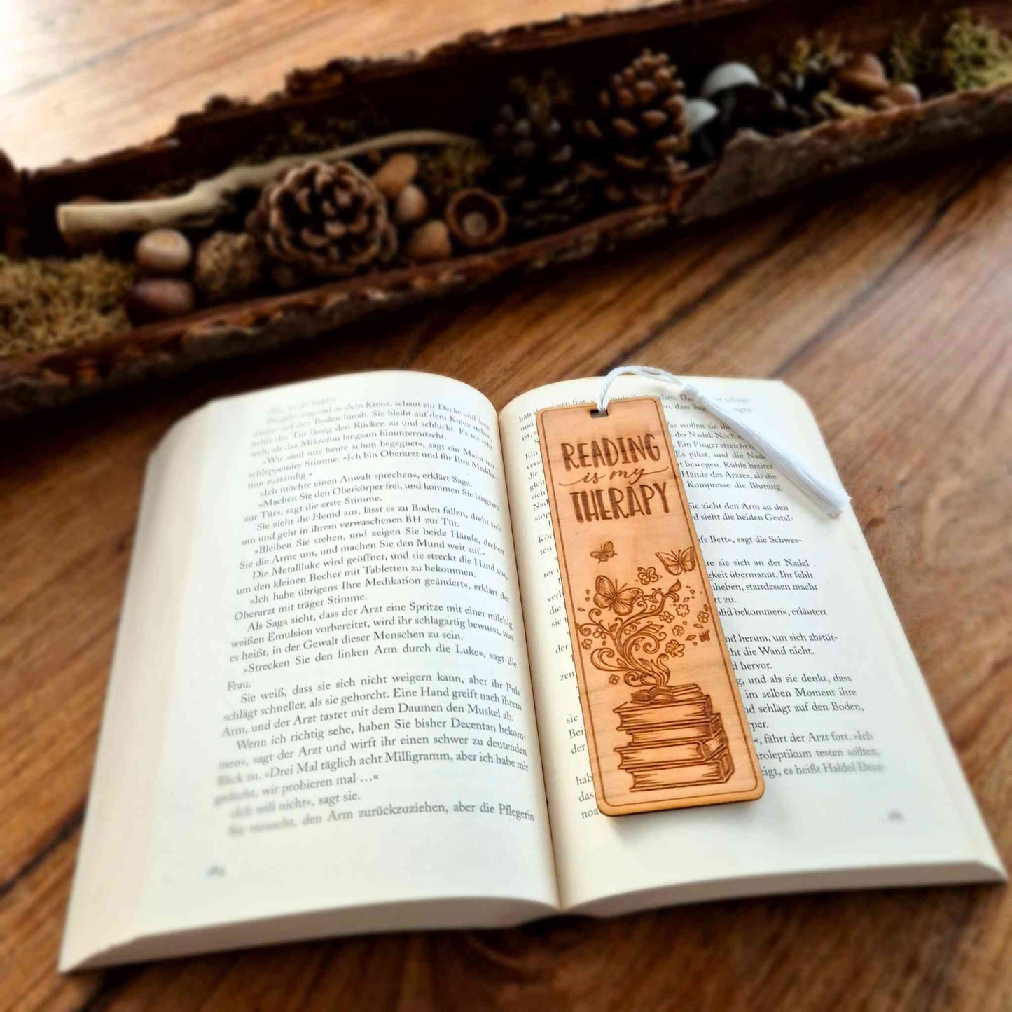Lesezeichen aus Kirschbaumholz mit einer Gravur des Spruchs " Reading is my therapy" und einem Buchmotiv