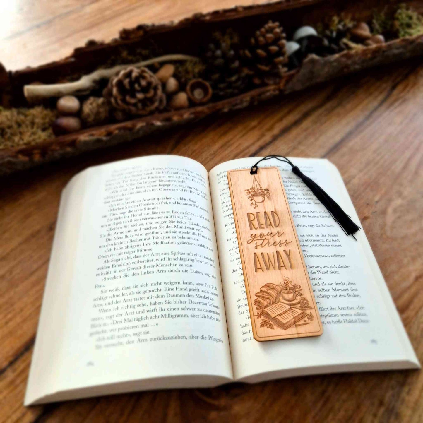 Lesezeichen aus Kirschbaumholz mit einer Gravur des Spruchs " Read your stress away" und einem Buchmotiv