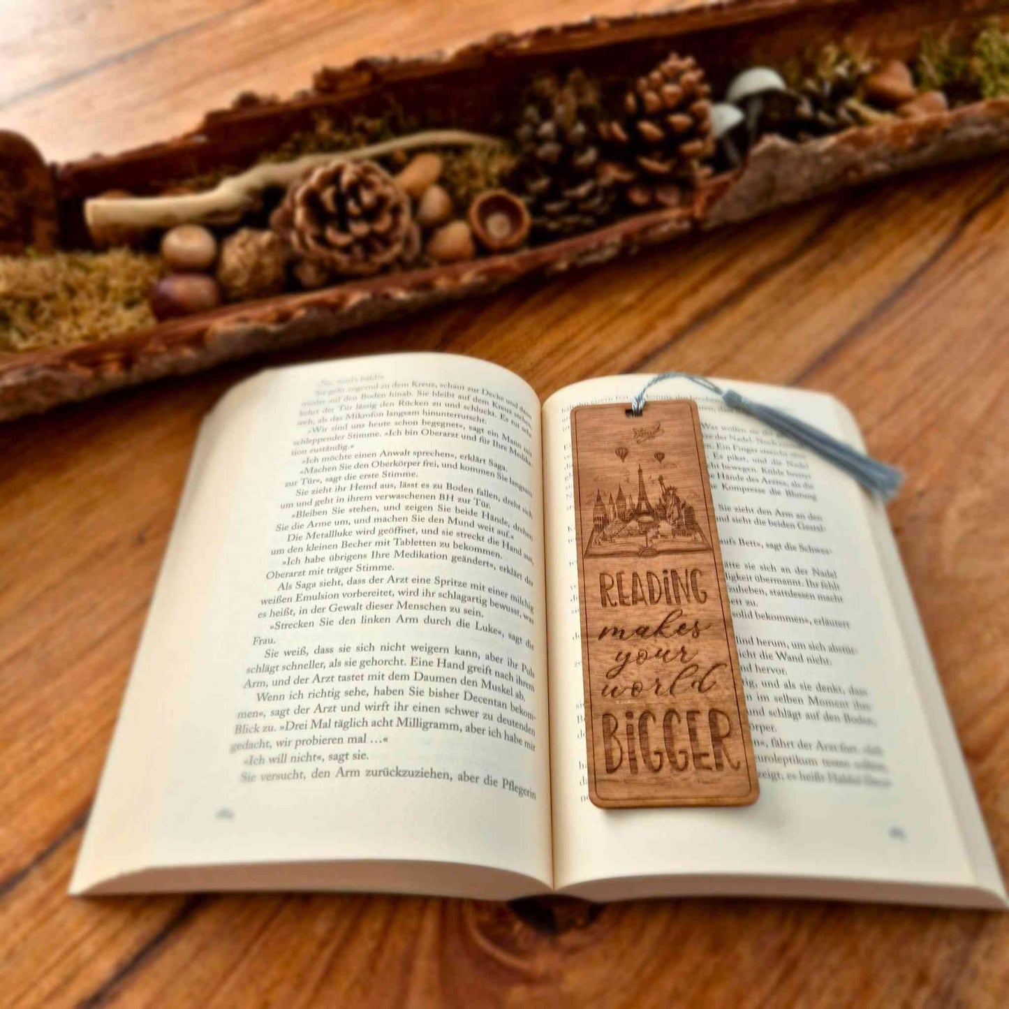 Lesezeichen aus Nussbaum mit graviertem Motiv und dem Spruch: Reading makes your world bigger
